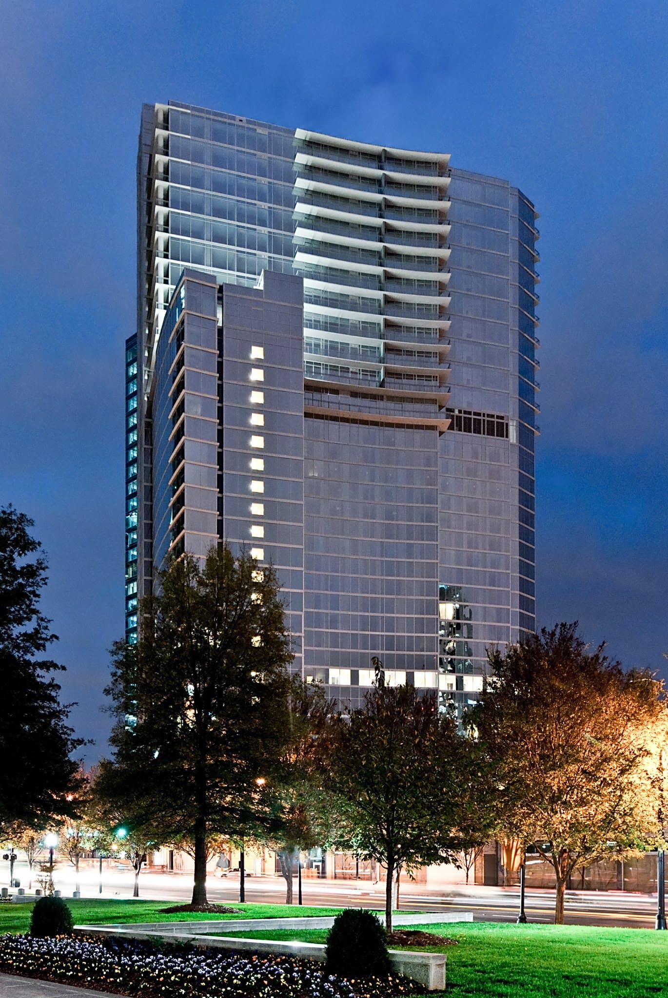 A sleek, modern hotel room at Loews Atlanta featuring floor-to-ceiling windows overlooking the Midtown skyline and a plush window seat.