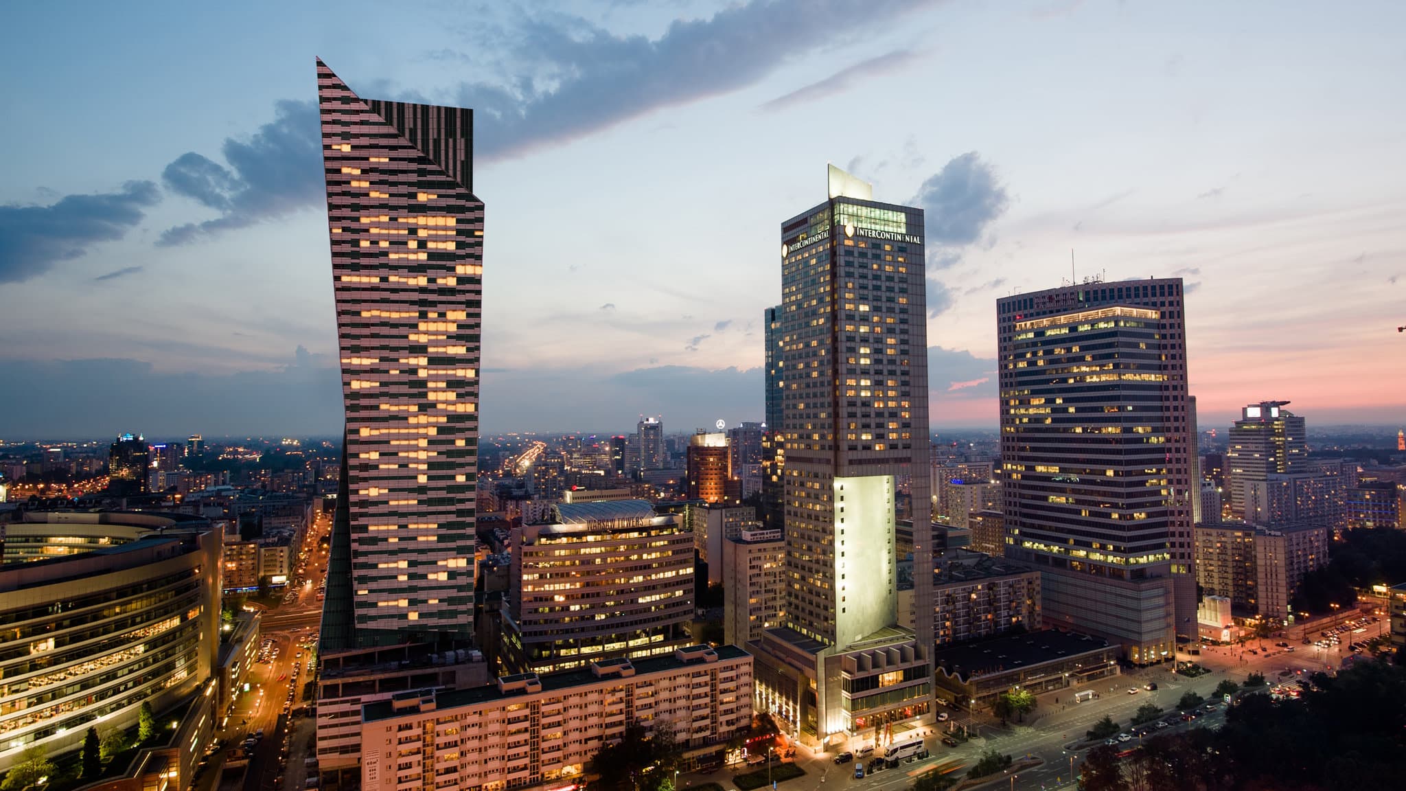 Swimmer in the 43rd-floor pool at InterContinental Warszawa overlooking the illuminated Palace of Culture and Science at night.