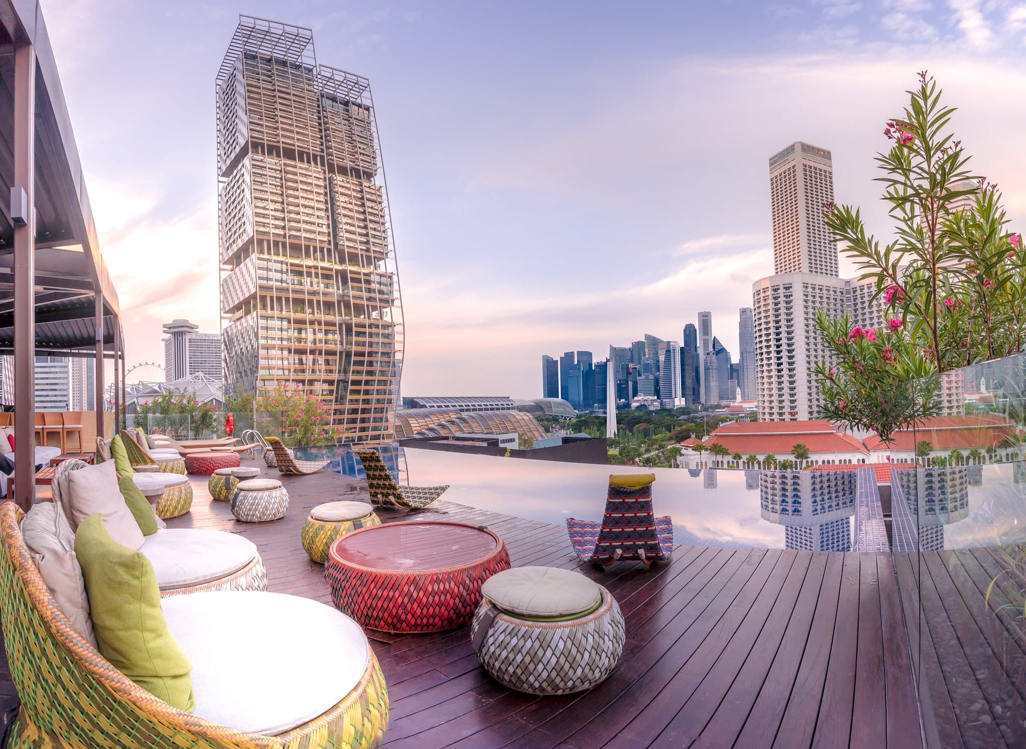 Naumi Hotel Singapore rooftop infinity pool at sunset with Marina Bay Sands skyline view.