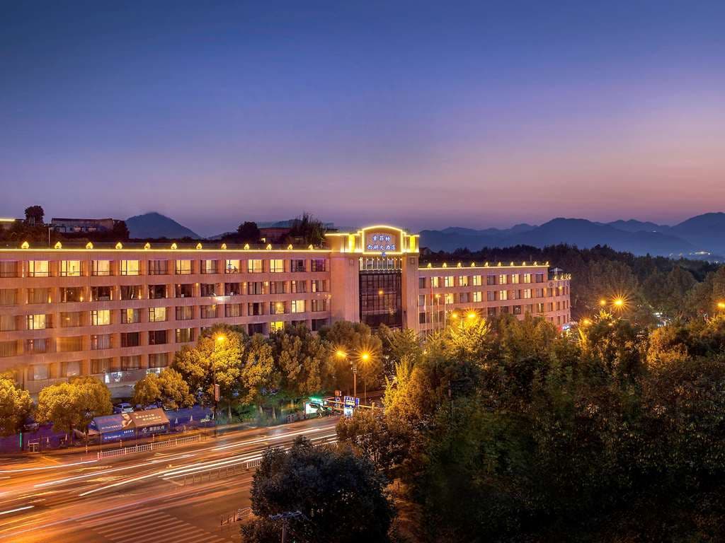 A panoramic twilight view of West Lake from the Sofitel Sky Garden terrace, featuring lounge seating and soft lighting.
