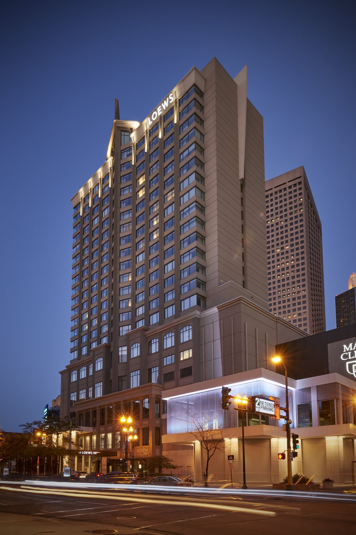 A sleek, modern hotel room at The Lofton Minneapolis featuring a baby grand piano and floor-to-ceiling windows overlooking the city skyline.