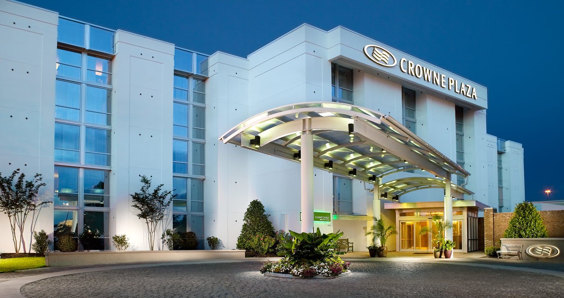 A sun-drenched outdoor pool terrace at Crowne Plaza Charleston with lounge chairs and parasols.