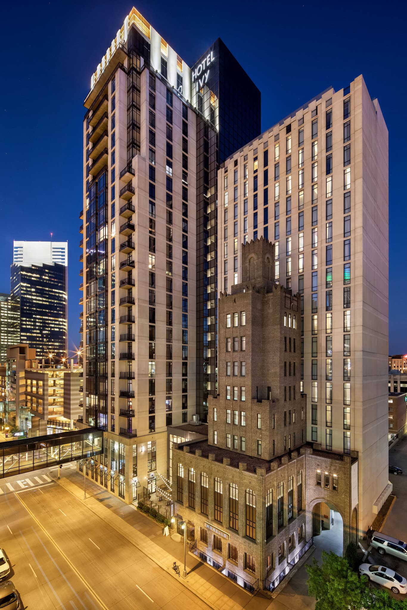 A minimalist Hotel Ivy suite featuring a deep limestone soaking bathtub with a view of the Minneapolis skyline through large windows.