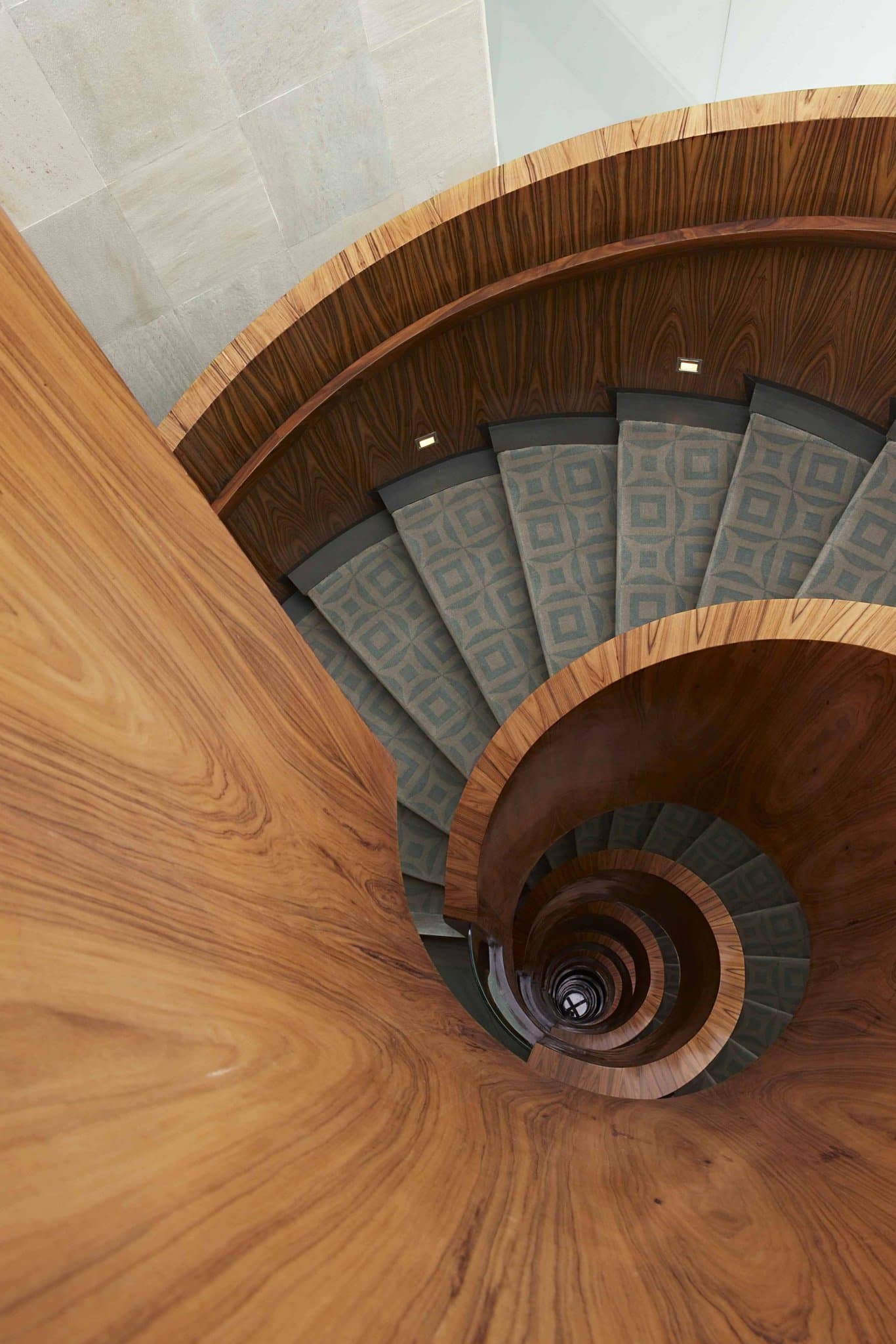 A dramatic, sculptural rosewood spiral staircase winding through the lobby of Las Alcobas Mexico City.