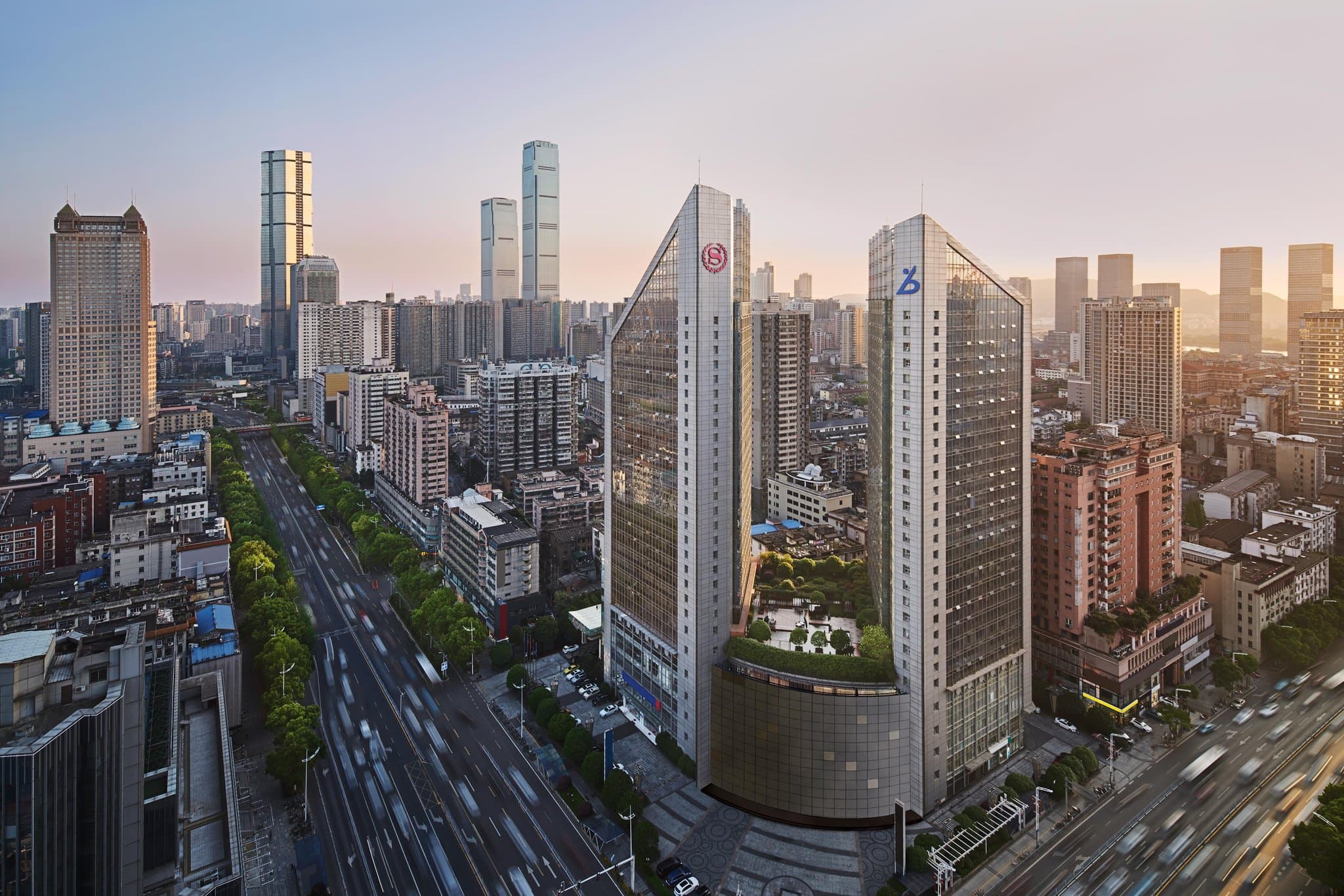 A dramatic shot of the Sheraton Changsha's indoor pool with blue mood lighting, showing the glass connection to the outdoor Sky Garden.