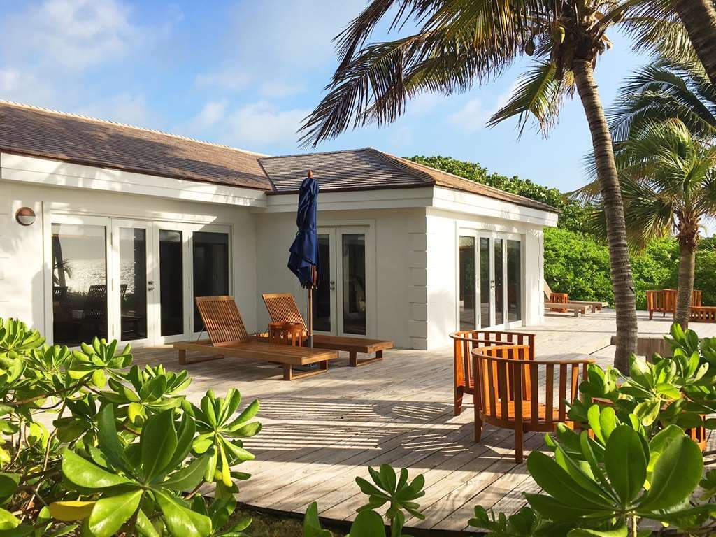 A secluded wooden cottage deck at Pink Sands Resort overlooking lush tropical foliage and the distant turquoise ocean.