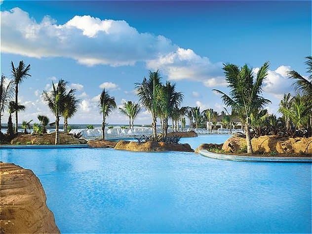 The Reef at Atlantis exterior tower rising above the exclusive Cascades Pool and white sand Paradise Beach.