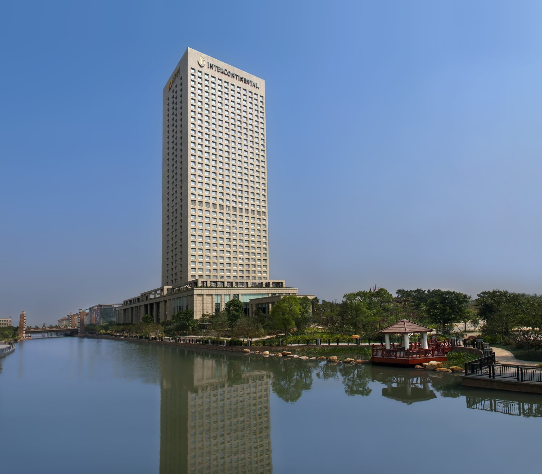 High-angle view of the InterContinental Foshan outdoor pool deck overlooking Qiandeng Lake at twilight.