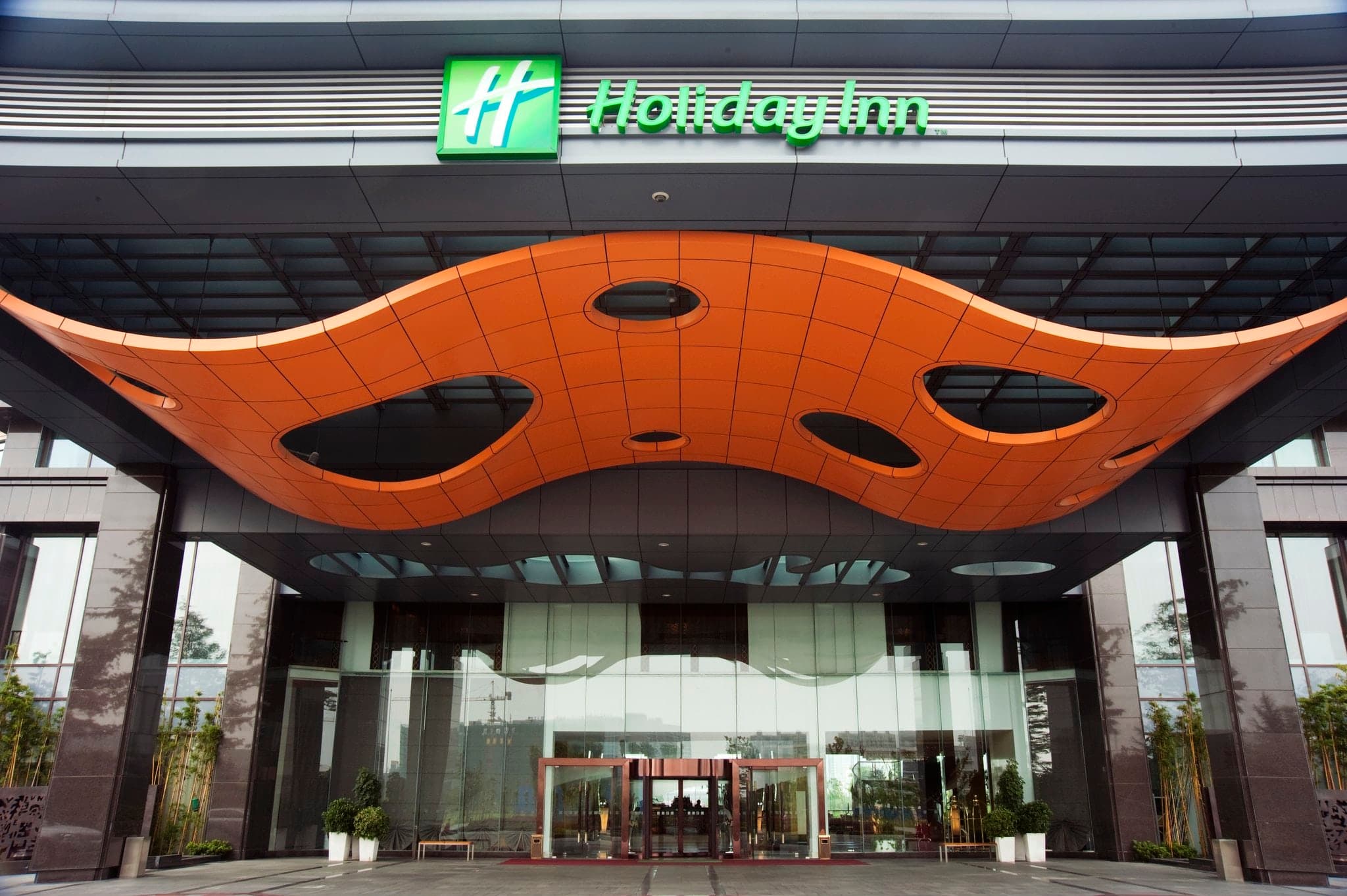 Expansive marble lobby atrium of Holiday Inn Changzhou Wujin featuring a black grand piano and warm lighting.