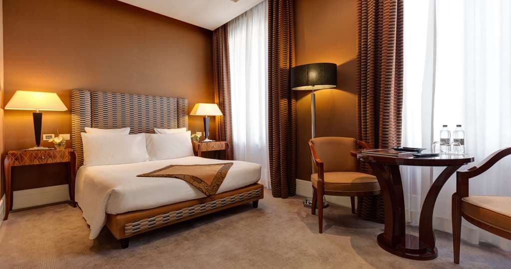 해질녘 Nobu Hotel Roma 파사드의 로우 앵글 샷, 역사적인 로마 건축물과 로비의 따뜻하고 현대적인 조명의 조화.