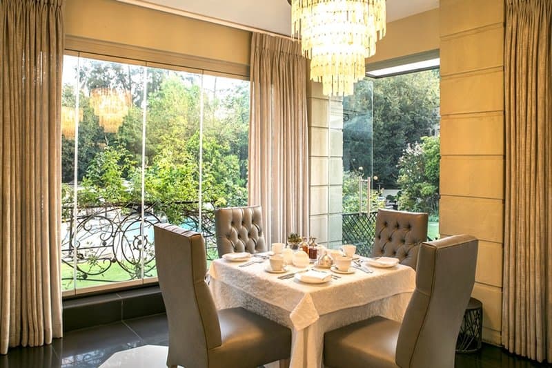 A lush, manicured lawn at Fairlawns Boutique Hotel with a high tea setup in the foreground and the columned manor house in the background.