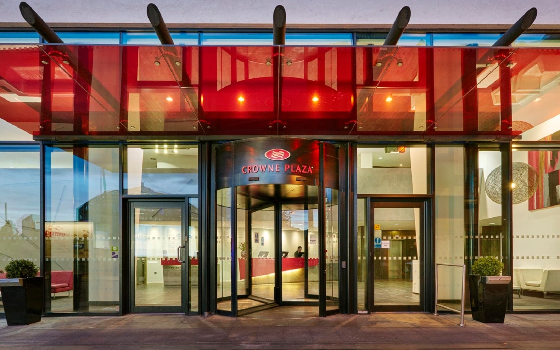 The Crowne Plaza Manchester City Centre's modern glass façade reflecting the sky, contrasting with the historic Northern Quarter architecture.