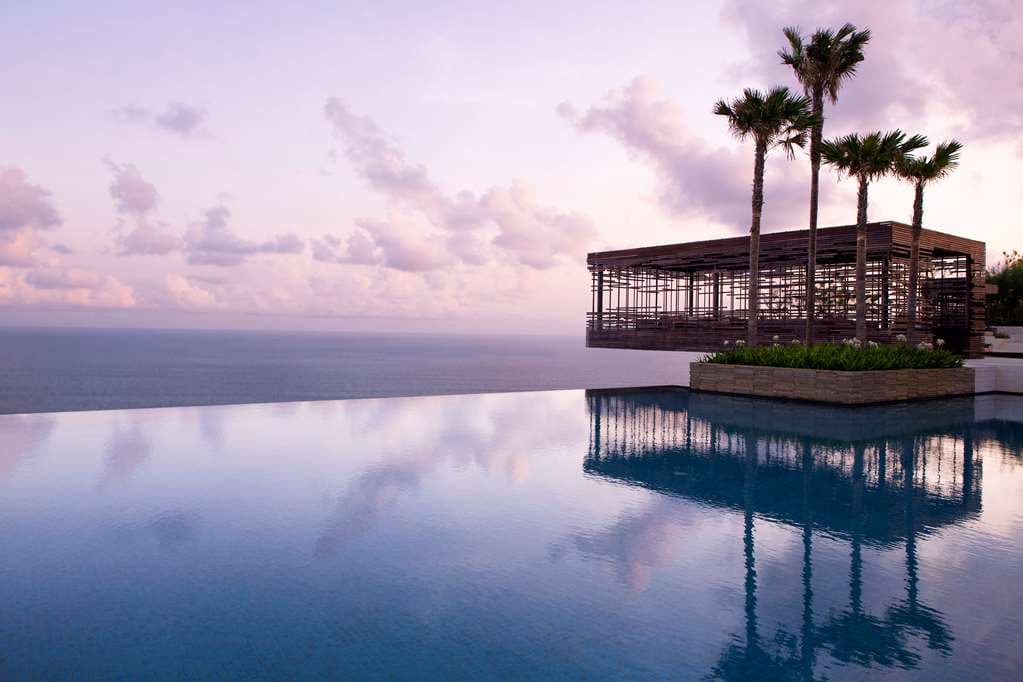 The iconic cantilevered wood-slatted Sunset Cabana at Alila Villas Uluwatu hanging over a limestone cliff with the deep blue Indian Ocean below.