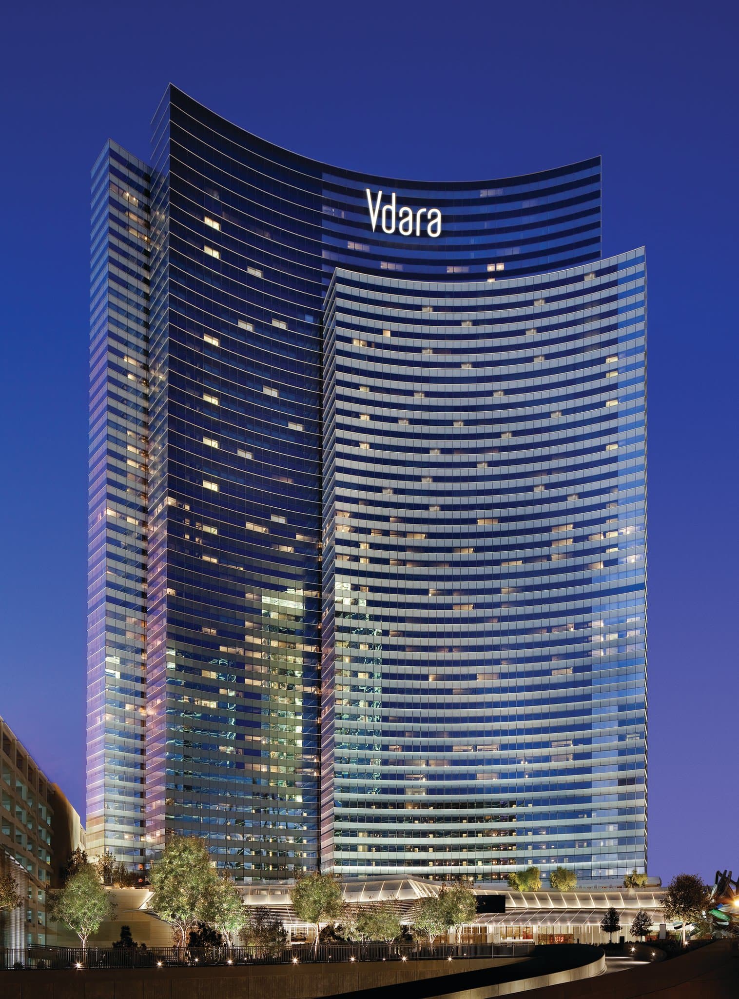입구의 화려한 'Big Edge' 카누 조각상 뒤로 솟아 있는 Vdara Hotel Las Vegas의 곡선형 유리 파사드.