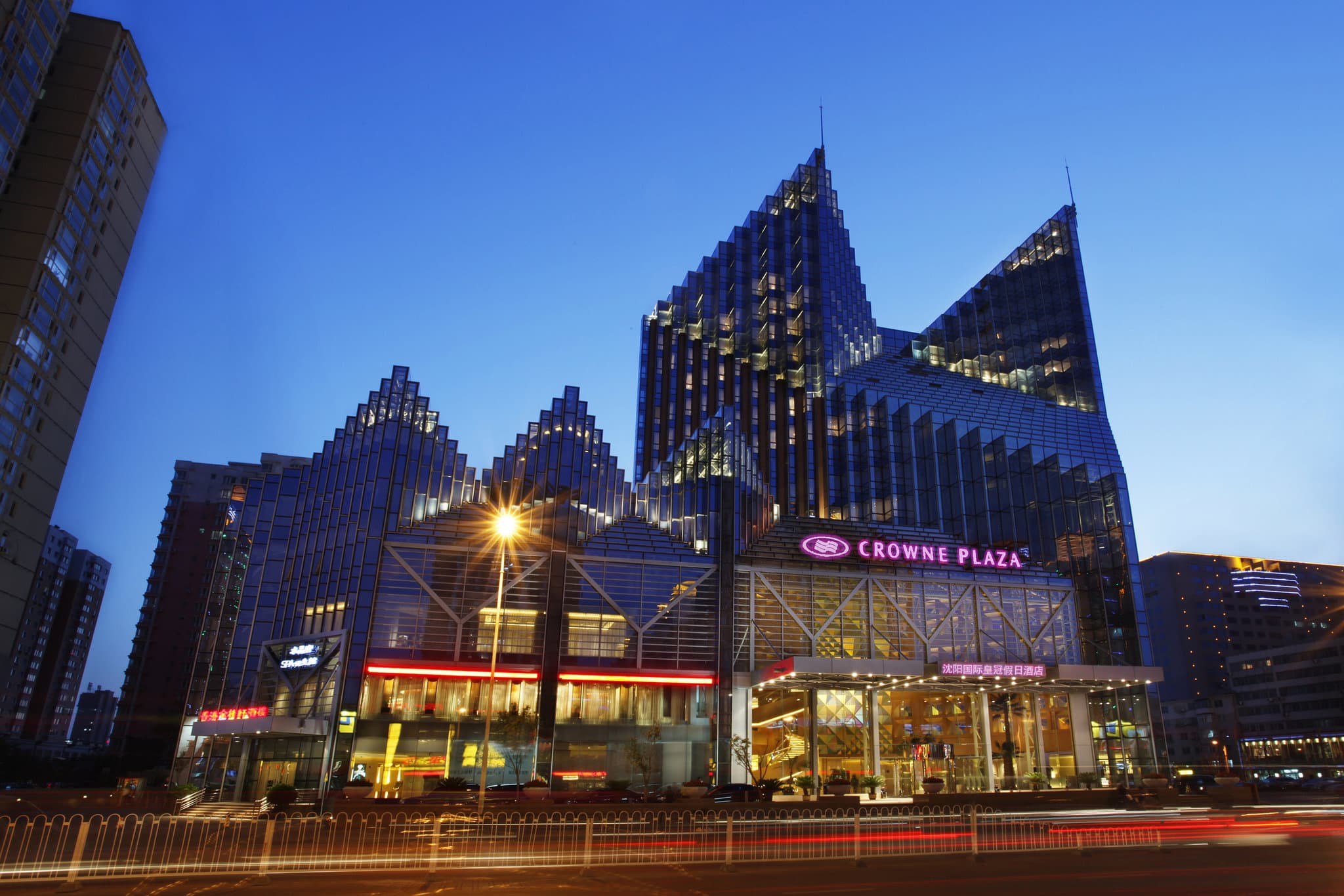 A dramatic low-angle shot of the Shenyang Parkview's diamond-faceted glass towers reflecting the warm golden hues of a Shenyang sunset.