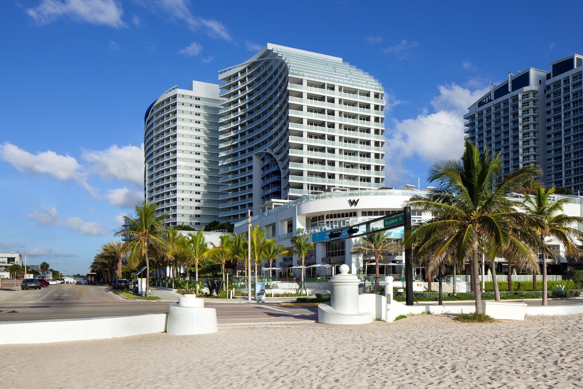 The translucent glass staircase cutting through the water of the WET East pool at W Fort Lauderdale, surrounded by Art Deco tiling and sun loungers.