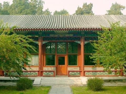 A traditional Chinese courtyard covered in snow with red lanterns glowing warmly against the twilight.