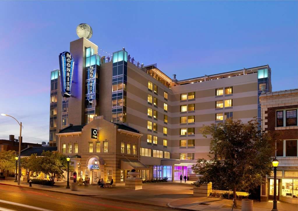 ライトアップされた回転する月の看板とダイニングテーブルがあるThe Moonrise Hotelのルーフトップバーの夜景。