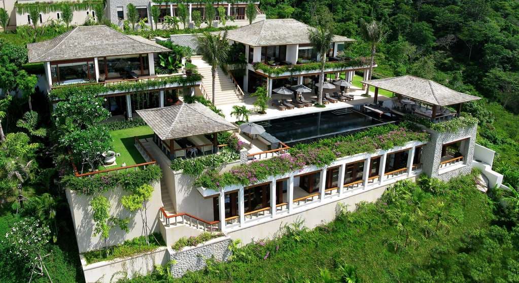 A sprawling private infinity pool at Andara Resort overlooking the Andaman Sea at twilight, framed by traditional Thai teak architecture.