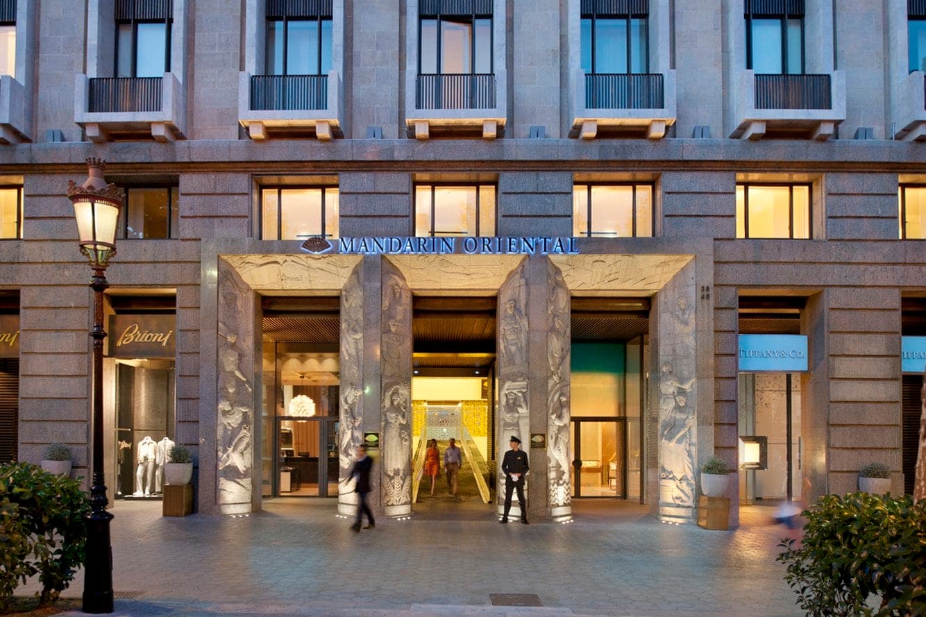 The dramatic 'Catwalk' entrance ramp of Mandarin Oriental Barcelona, illuminated by gold lattice screens and white interiors.