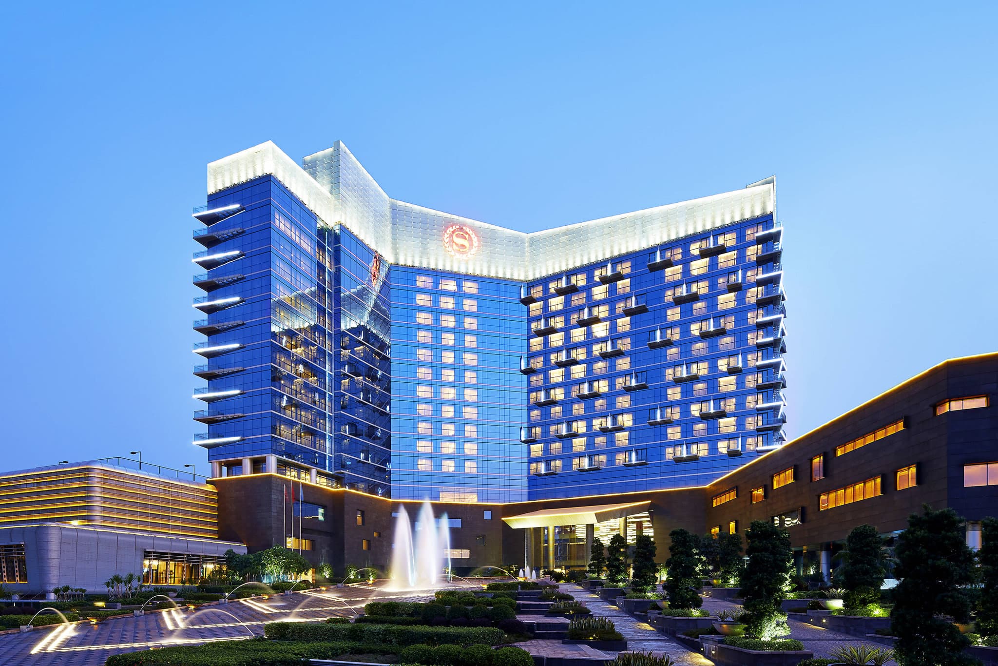 The semi-indoor heated swimming pool at Sheraton Shunde extending towards the outdoor garden.