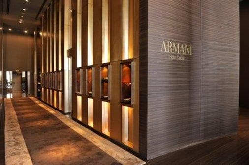 The lobby of Armani Hotel Dubai featuring curved tubular arches, Eramosa stone floors, and minimalist seating under warm amber lighting.