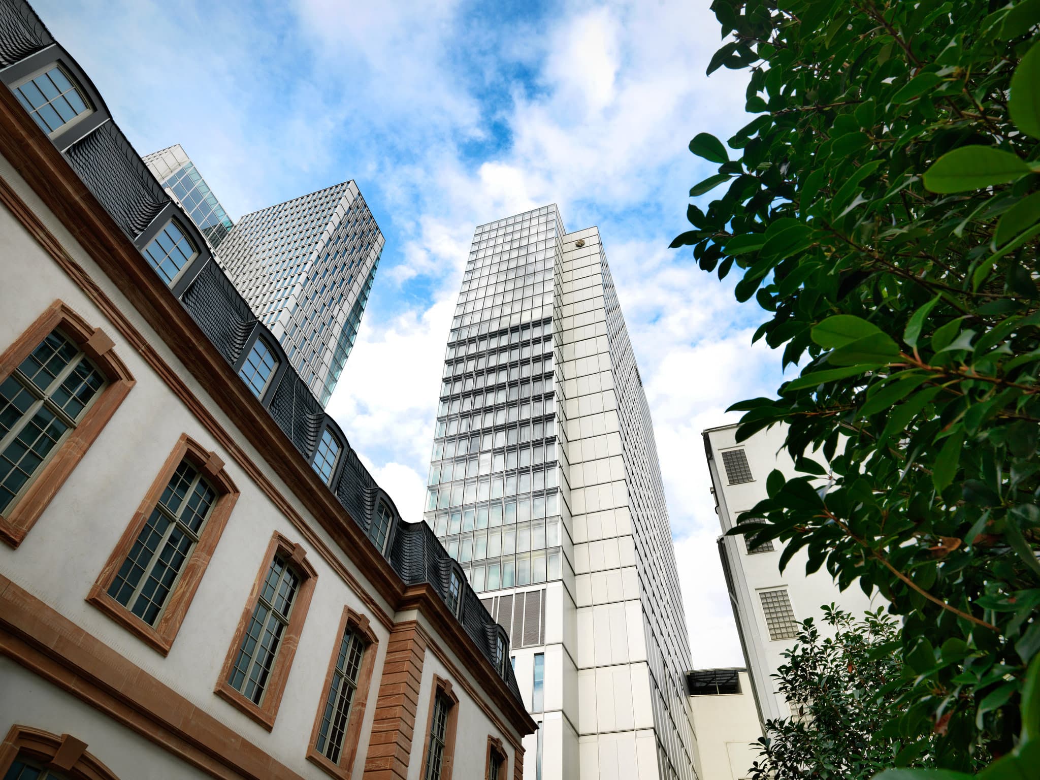 A guest room at JW Marriott Frankfurt featuring a vibrant Hartwig Ebersbach painting and floor-to-ceiling windows overlooking the city skyline.