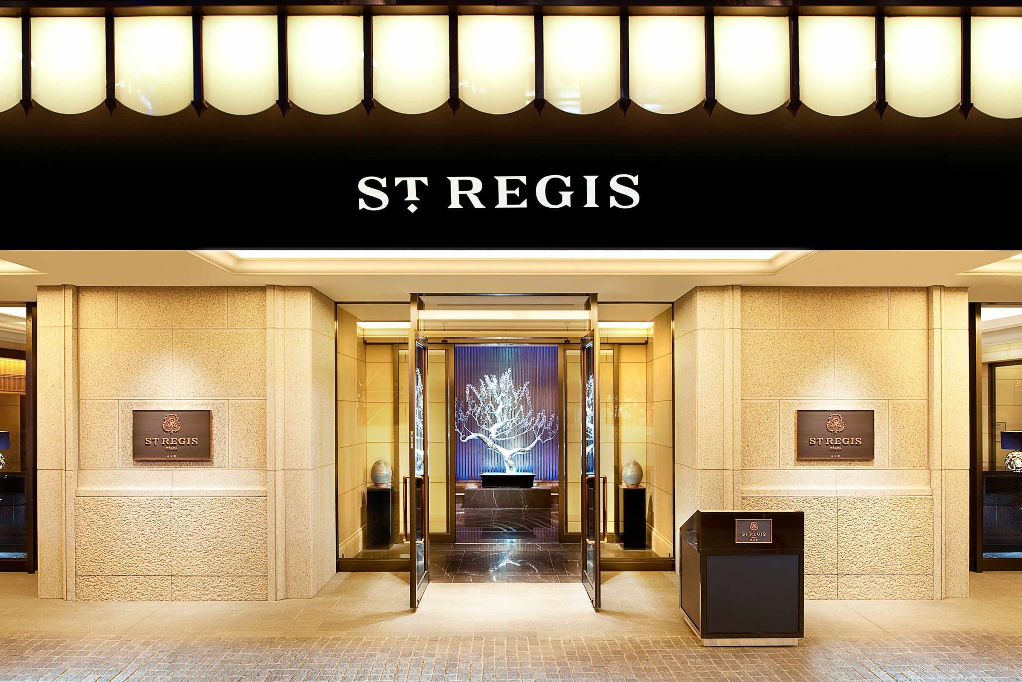 The moody, jazz-inspired interior of The St. Regis Bar in Osaka featuring a golden mural of Osaka Castle and plush velvet seating.