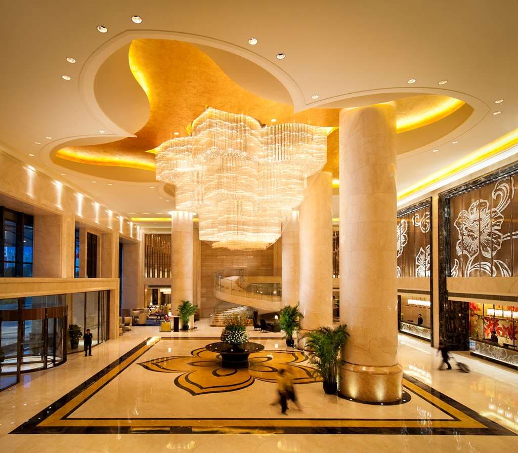 A dramatic low-angle shot of the Hilton Guangzhou Baiyun lobby featuring a massive crystal chandelier reflecting on polished marble floors.