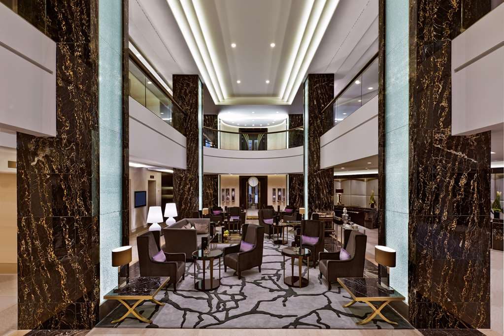A dramatic spiral staircase in the Waldorf Astoria Berlin lobby, framed by Art Deco lighting and the signature grandfather clock.