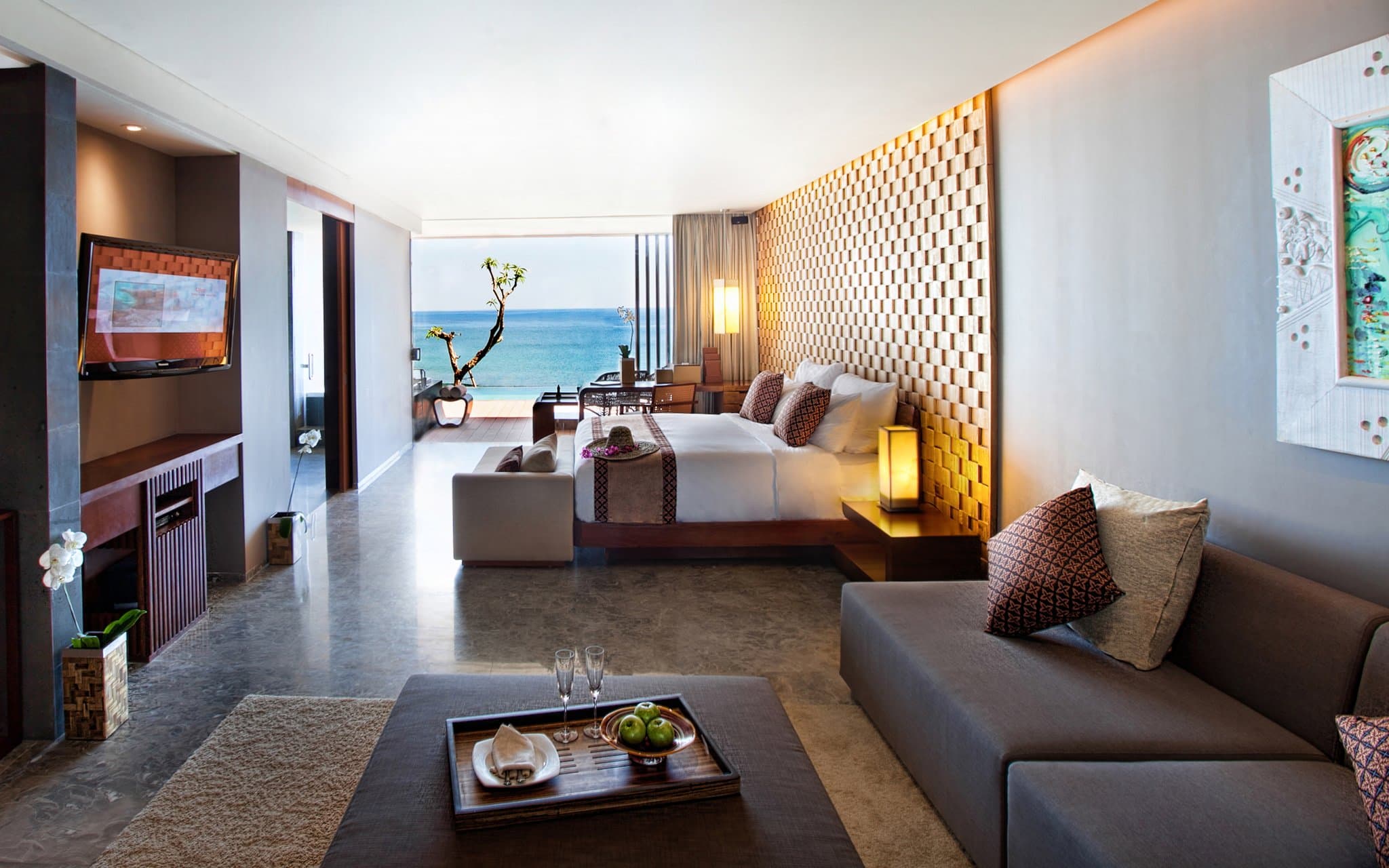 Anantara Uluwatu's split-level infinity pool cascading down the limestone cliff at sunset.