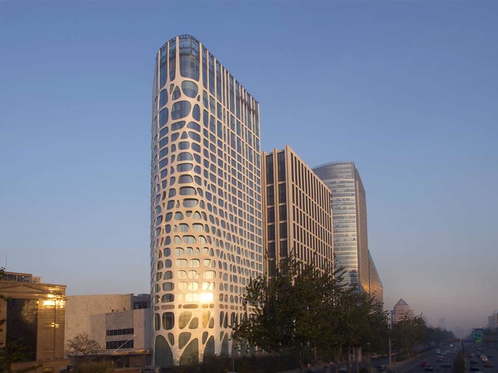 The white, undulating 'nervous tissue' facade of the Conrad Beijing rising organically against a blue sky.