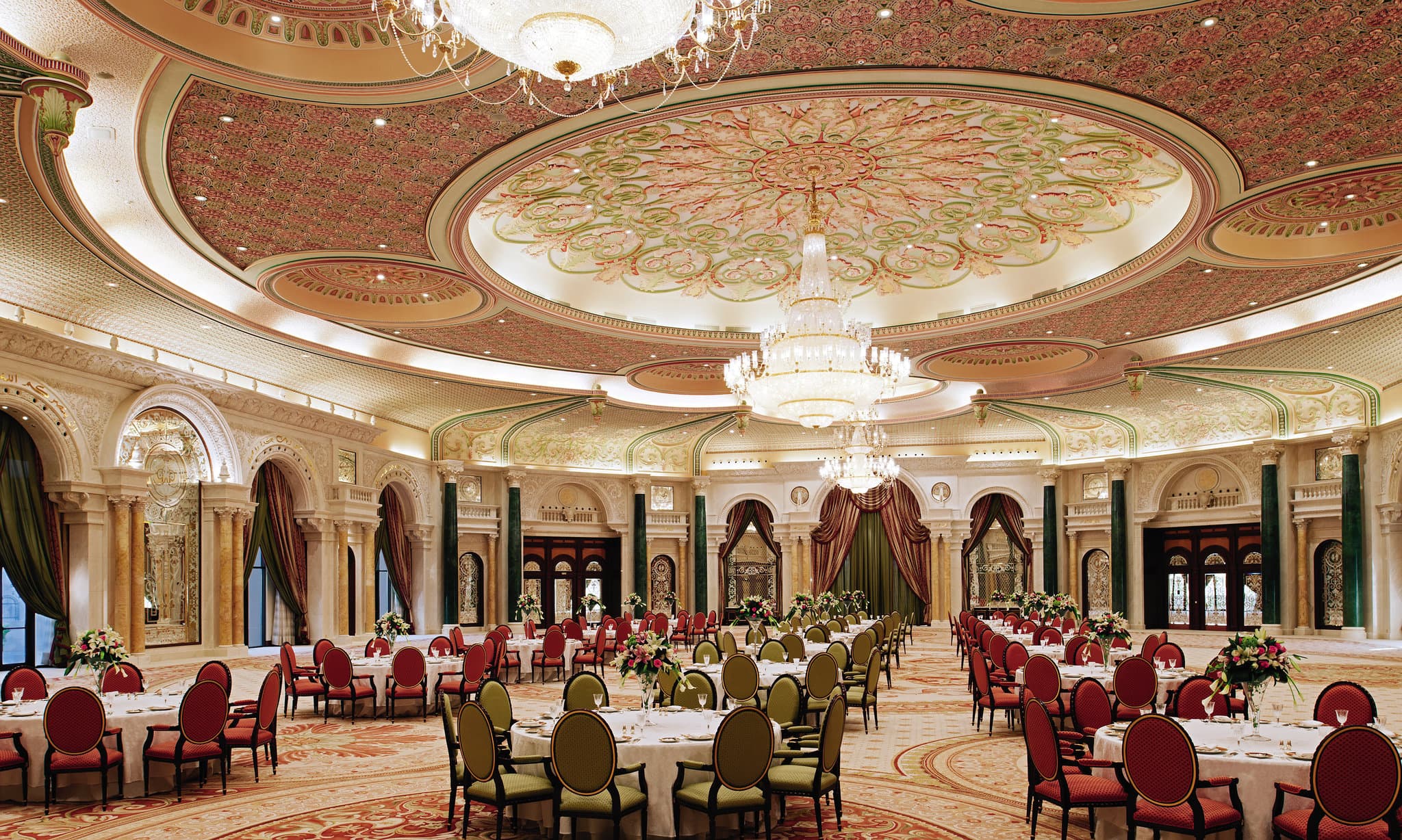 The Ritz-Carlton Riyadh indoor pool atrium featuring a grand vaulted ceiling and floor-to-ceiling arched windows.