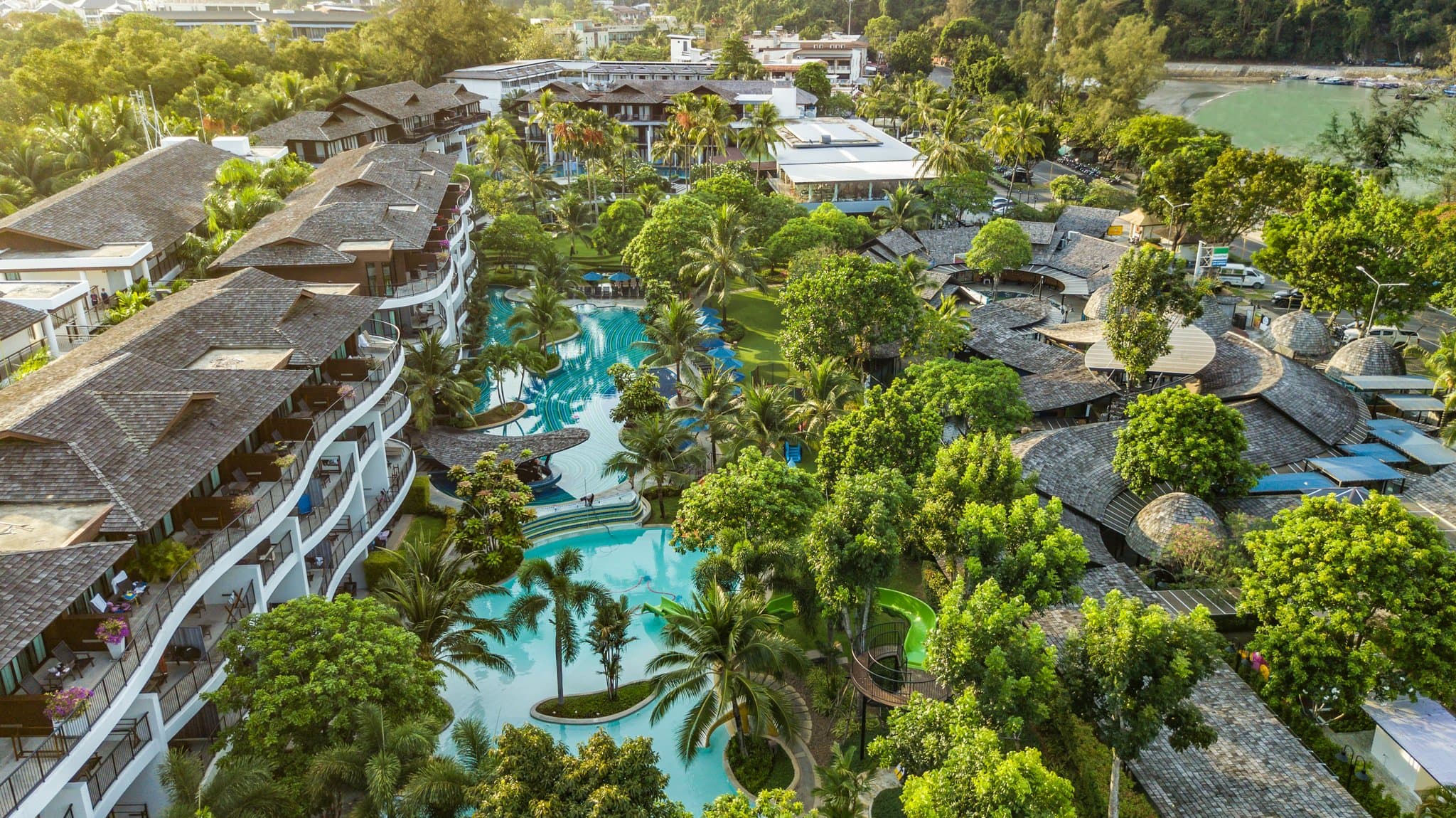 Aerial view of Holiday Inn Resort Krabi's massive free-form pool winding through palm trees with limestone cliffs in the background.
