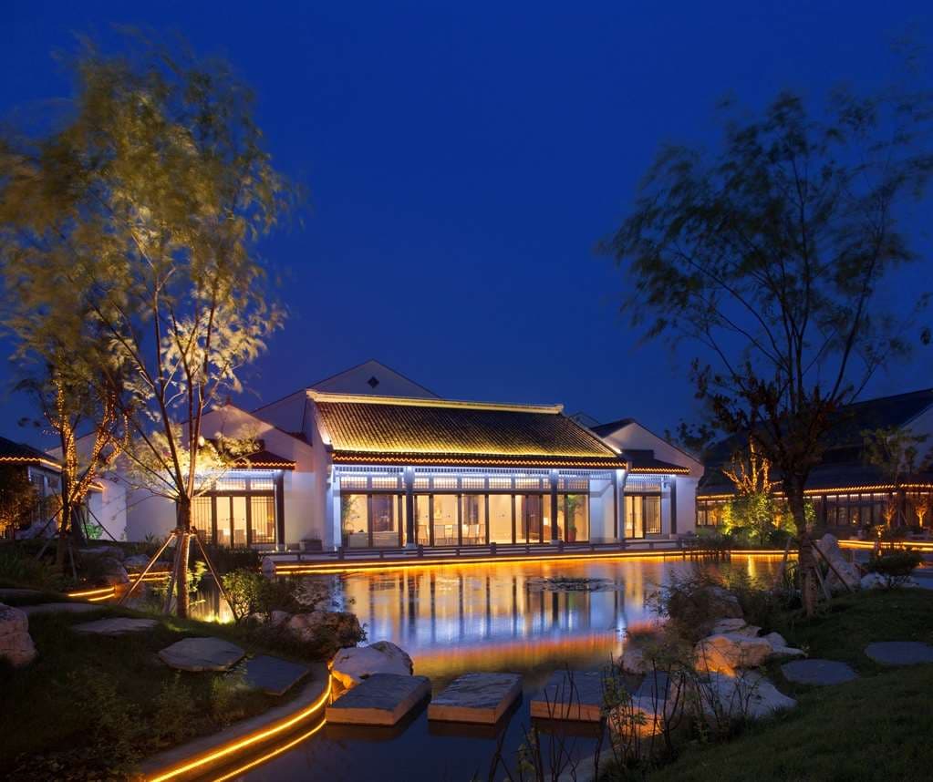 A serene central courtyard at Radisson Blu Wuxi featuring traditional Jiangnan architecture, calm water reflection, and wetland greenery.