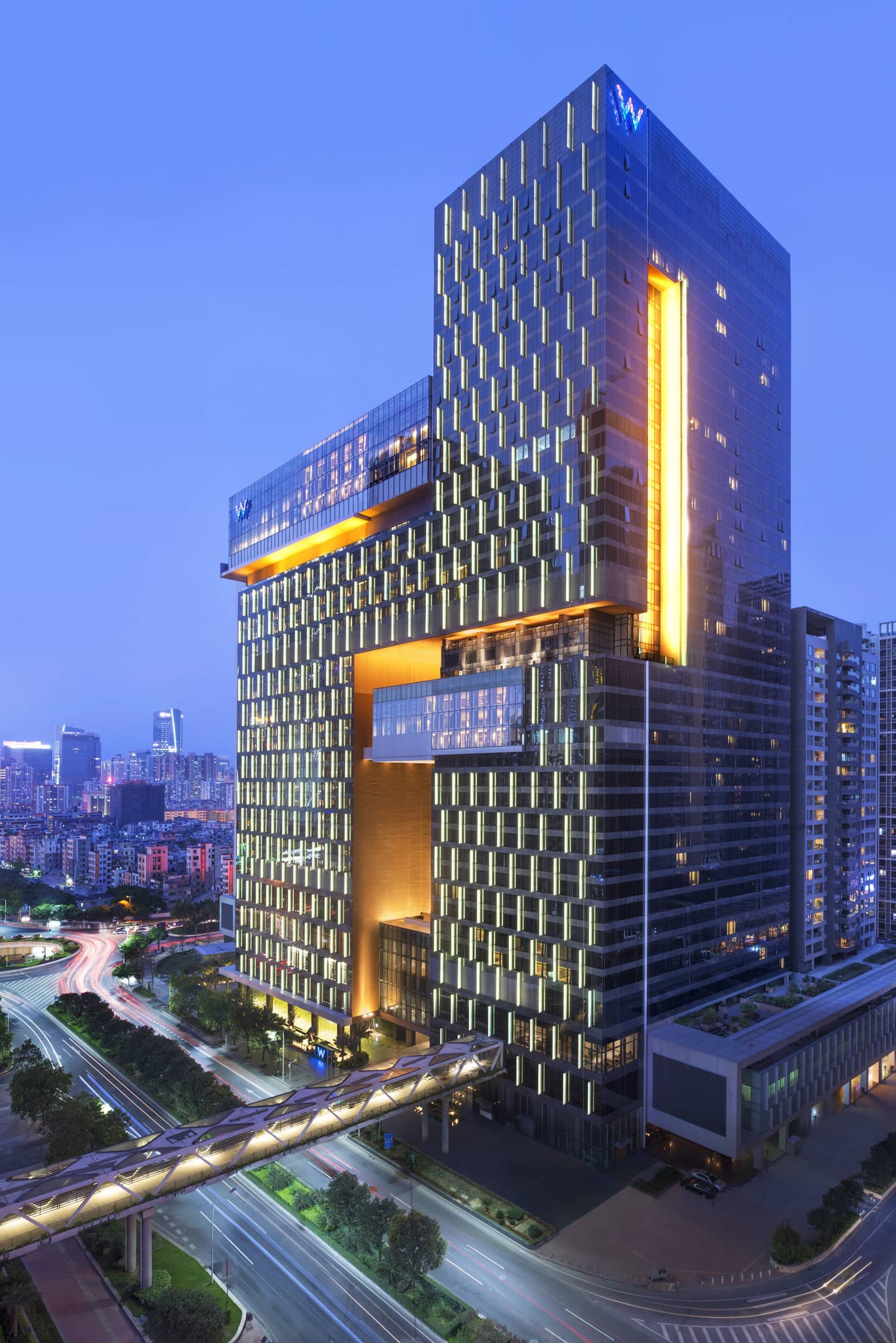 The asymmetrical black glass exterior of W Guangzhou designed by Rocco Yim, featuring the 19-meter Luminous Water Wall entrance at night.