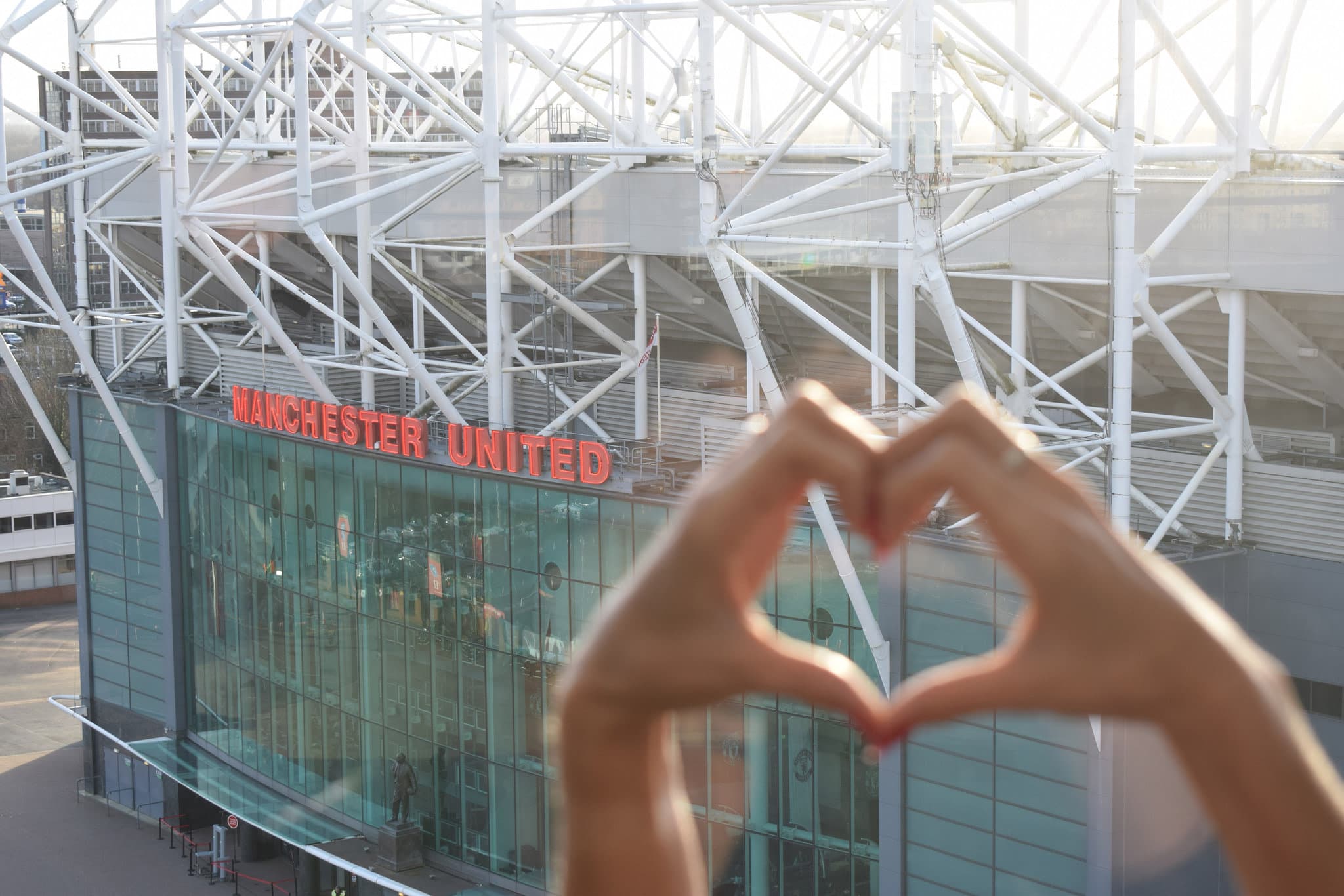 View from a Hotel Football bedroom window framing the Old Trafford stadium sign and red brick facade.