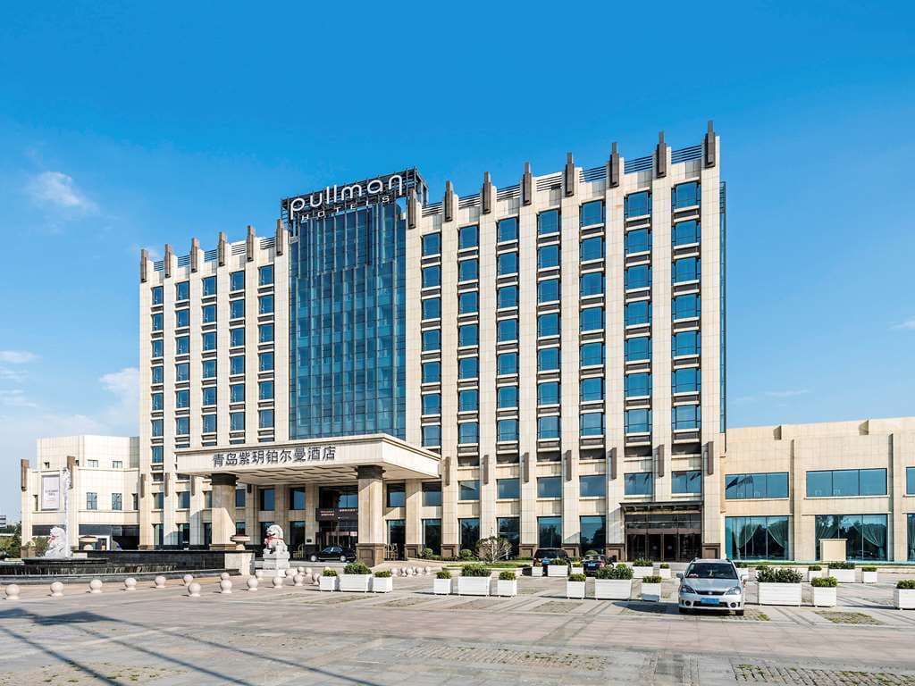 Exterior view of Pullman Qingdao Ziyue near Qingdao airport with modern facade and driveway entrance