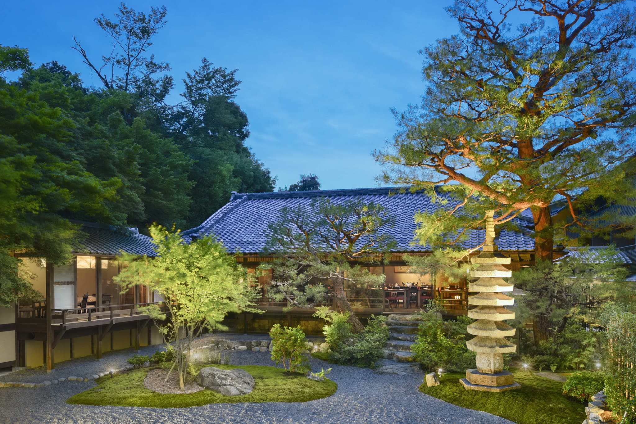 A private open-air onsen bath on a wooden terrace at Suiran Kyoto, overlooking the Hozu River and Arashiyama mountains.