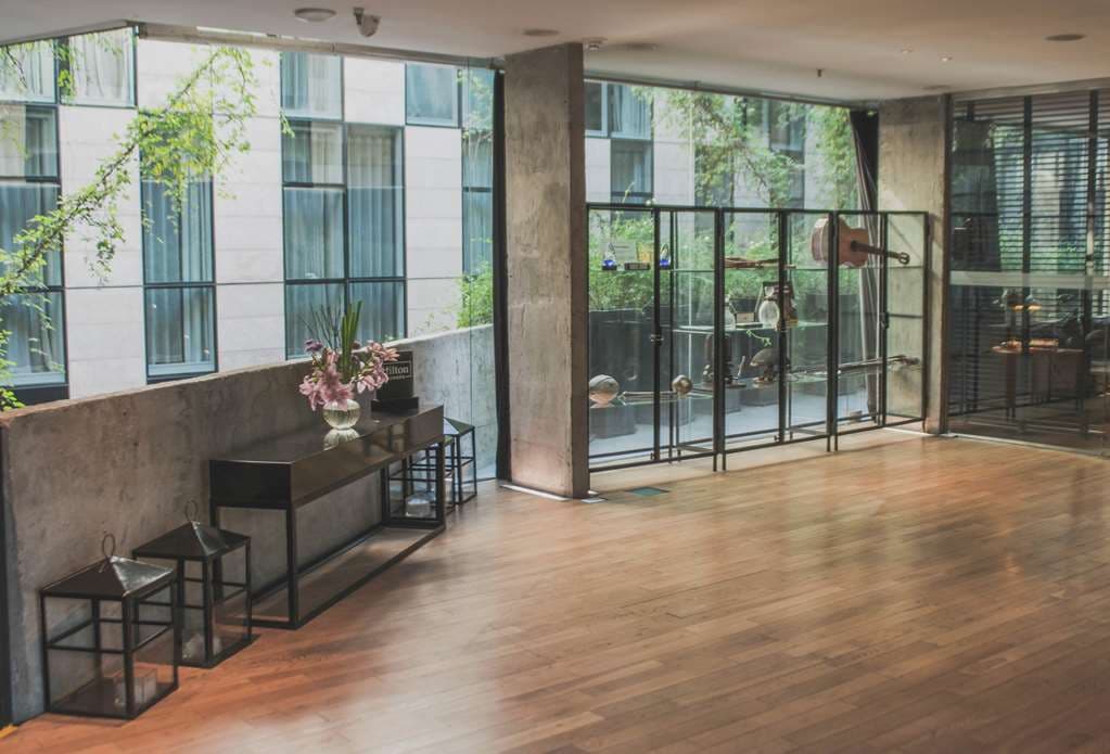 Anselmo Buenos Aires internal courtyard featuring vertical gardens, white bistro chairs, and industrial-chic architecture.