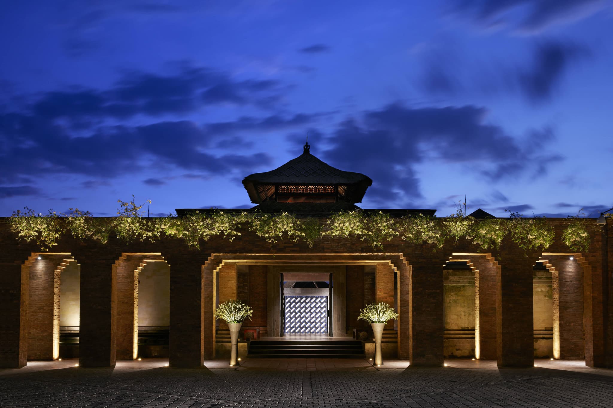 Private bamboo dining cocoons at Kubu restaurant illuminated by warm light at dusk, overlooking the Ayung River.
