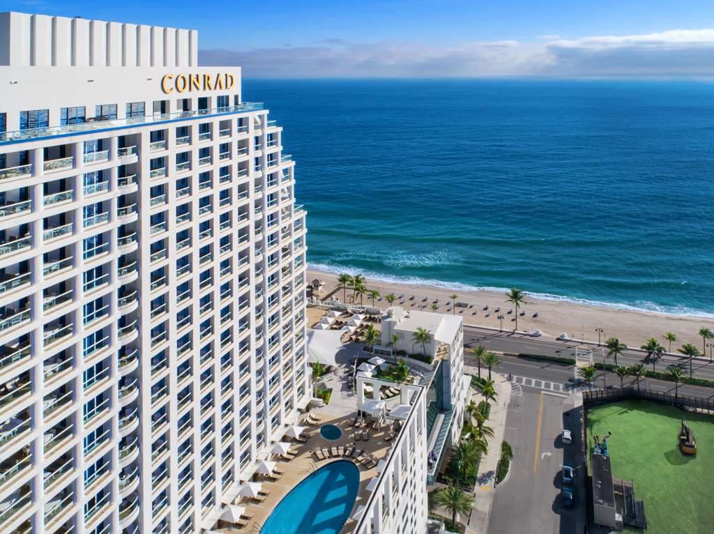 View from the Conrad Fort Lauderdale Sky Deck pool overlooking the Atlantic Ocean with white lounge chairs.