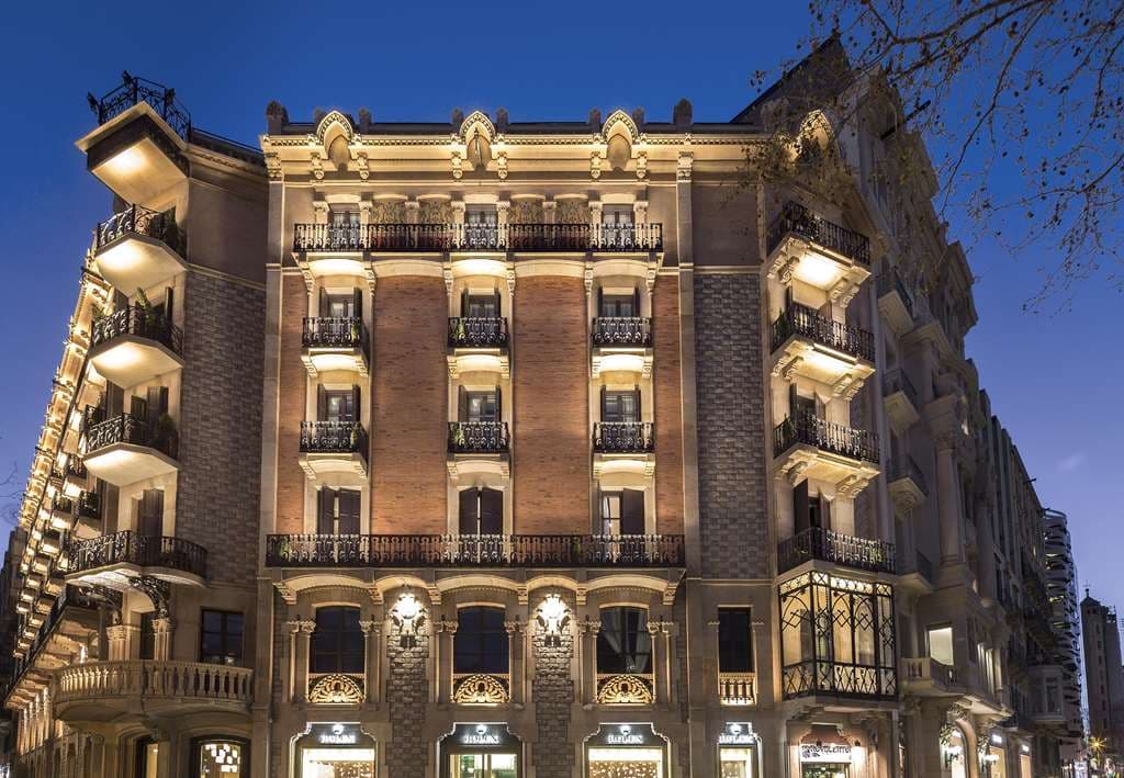 The Monument Hotel rooftop terrace pool at sunset featuring a direct view of Gaudí's La Pedrera chimneys.