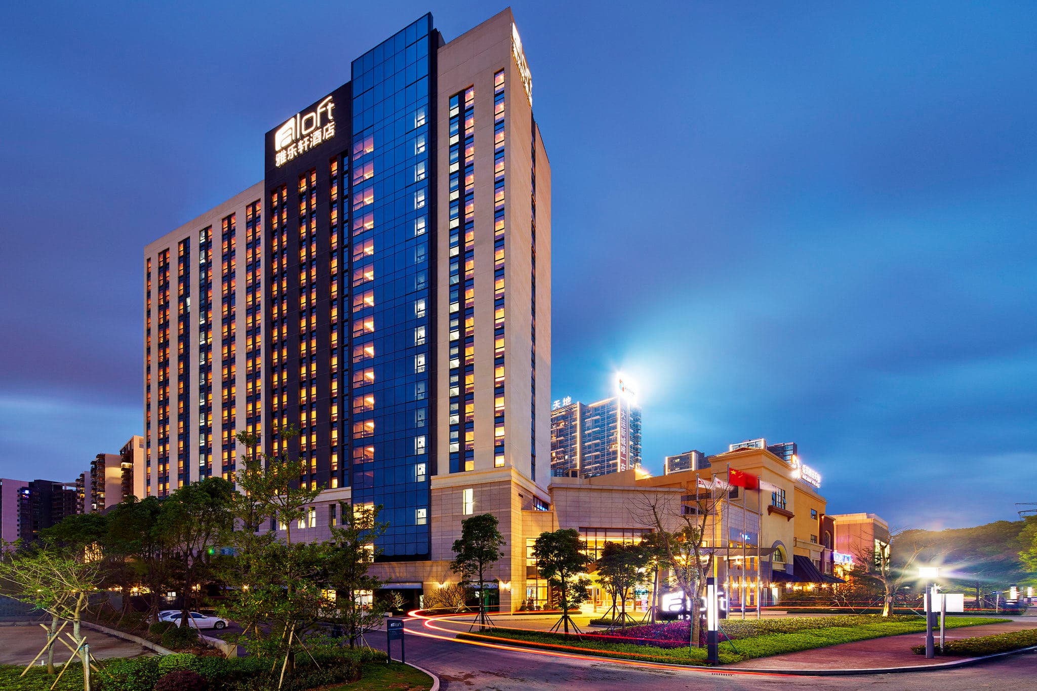 Aloft Dongguan Dynamic Town exterior at night featuring the W XYZ bar neon signage and the illuminated Kaleidoscope plaza.