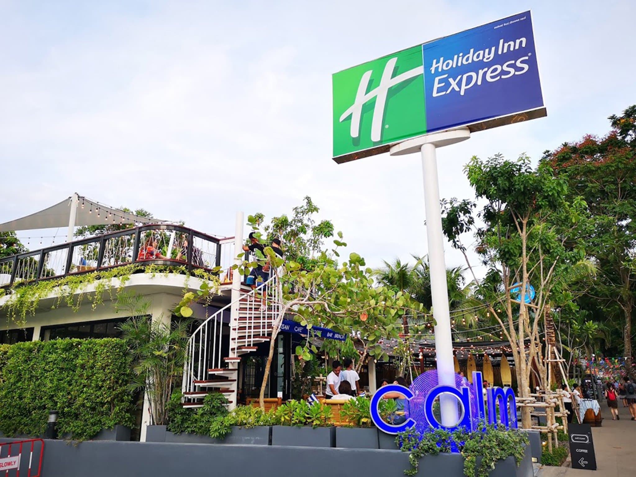 A vibrant view of the Holiday Style Ao Nang Beach Resort swimming pool with blue tiles, surrounded by modern white balconies and tropical greenery.