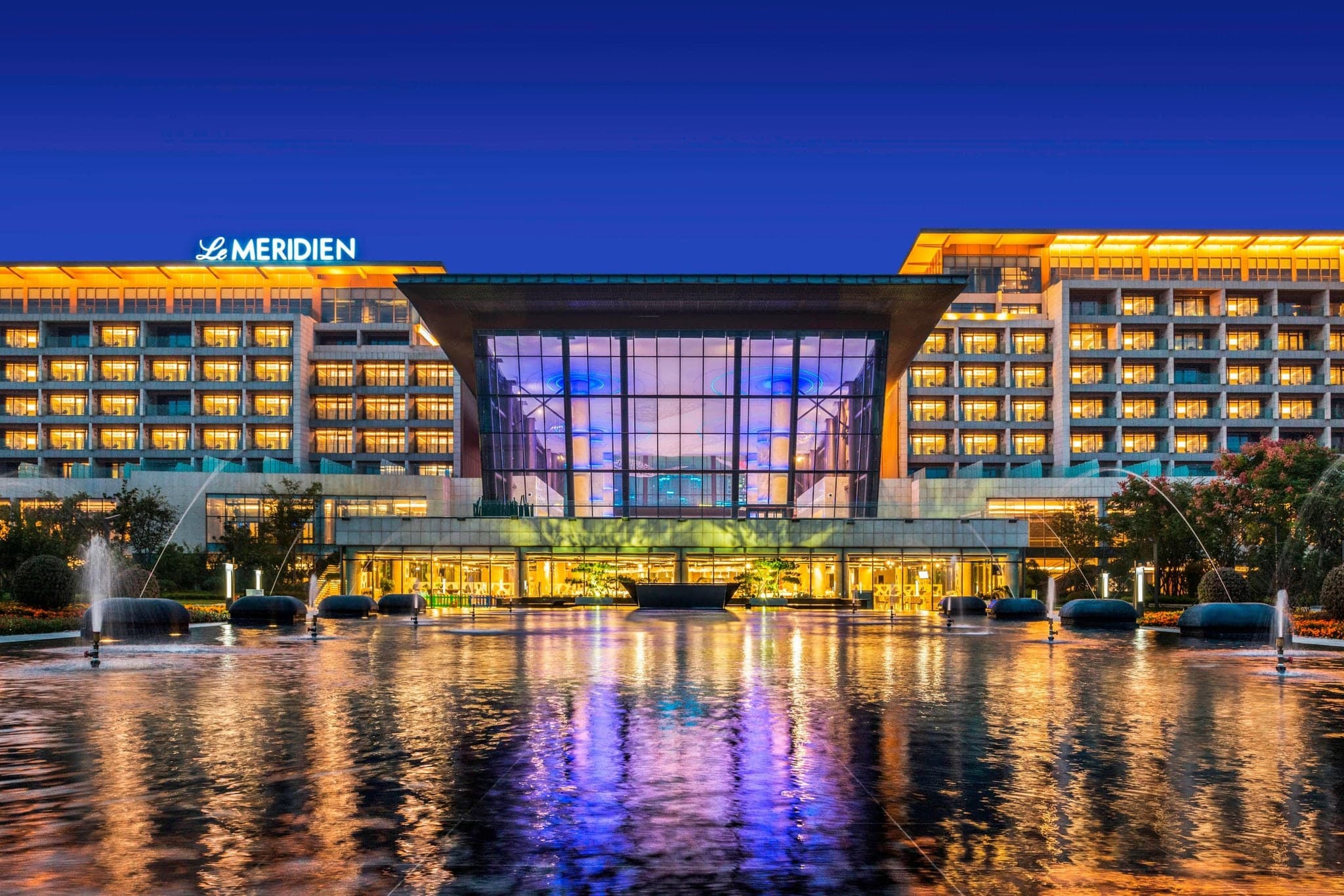 Le Méridien Qingdao West Coast Resort avant-garde lobby with artistic lighting and sea view backdrop.