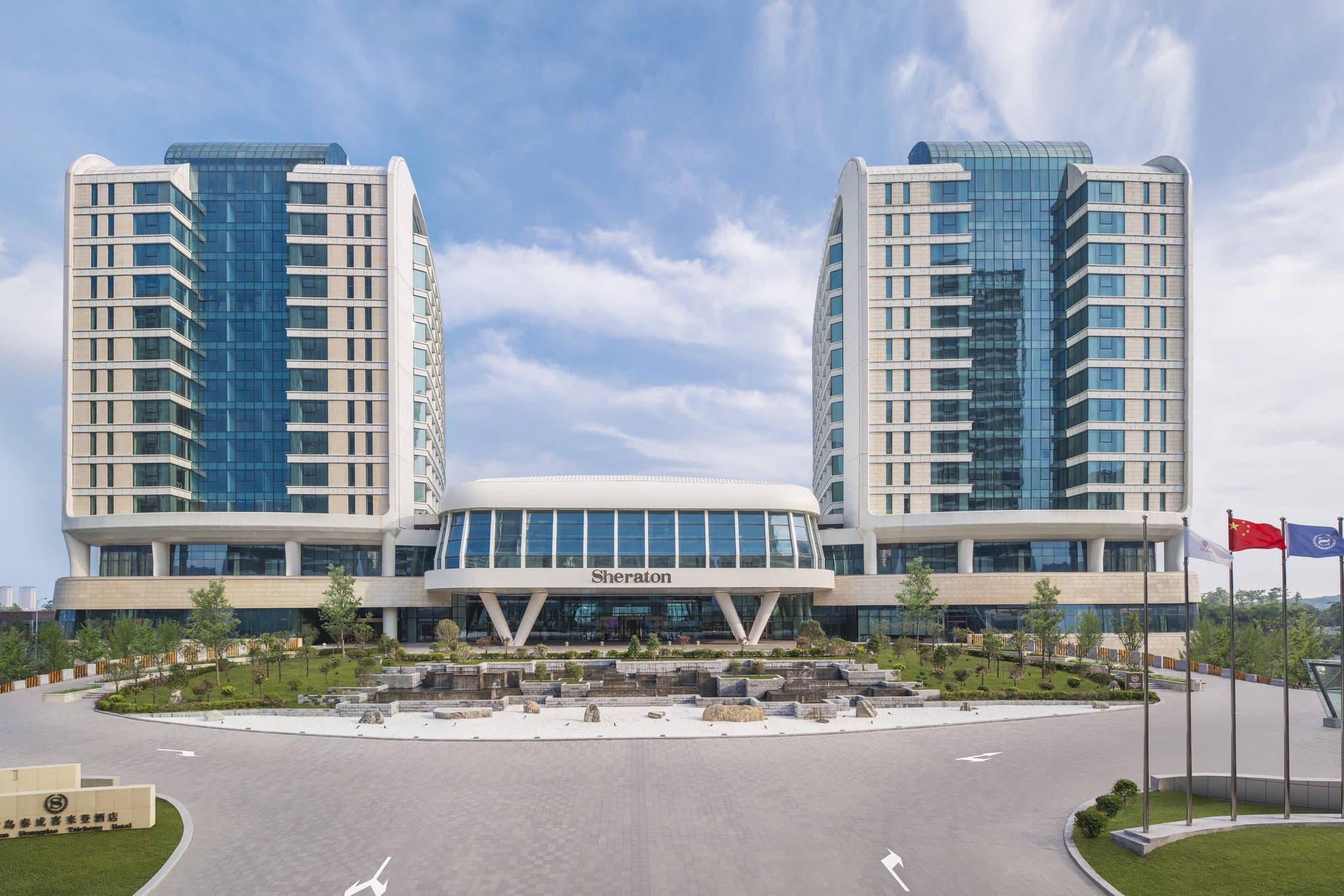The sail-shaped exterior of Sheraton Qingdao West Coast Hotel rising above Tangdao Bay.