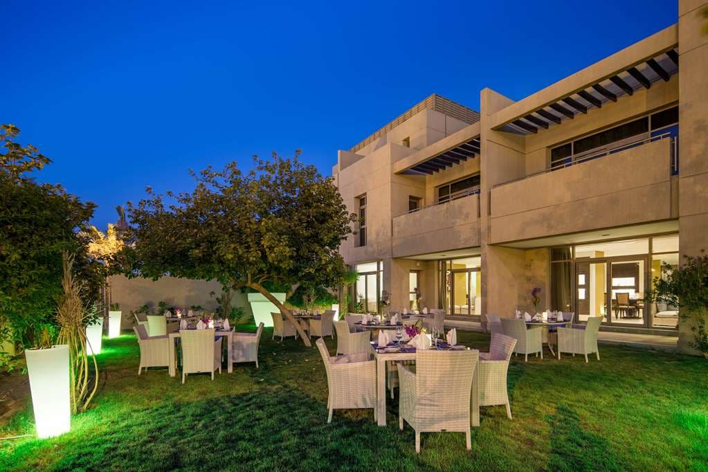 Twilight view of La Mesa restaurant terrace at Vivienda Granada, illuminated by floor lanterns with palm trees in the background.