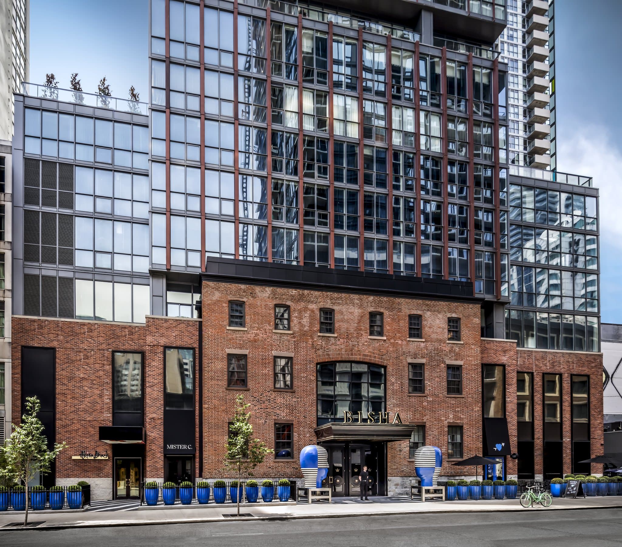 CNタワーを背景にしたBisha Hotel Torontoの屋上インフィニティプールとくつろぐゲスト。