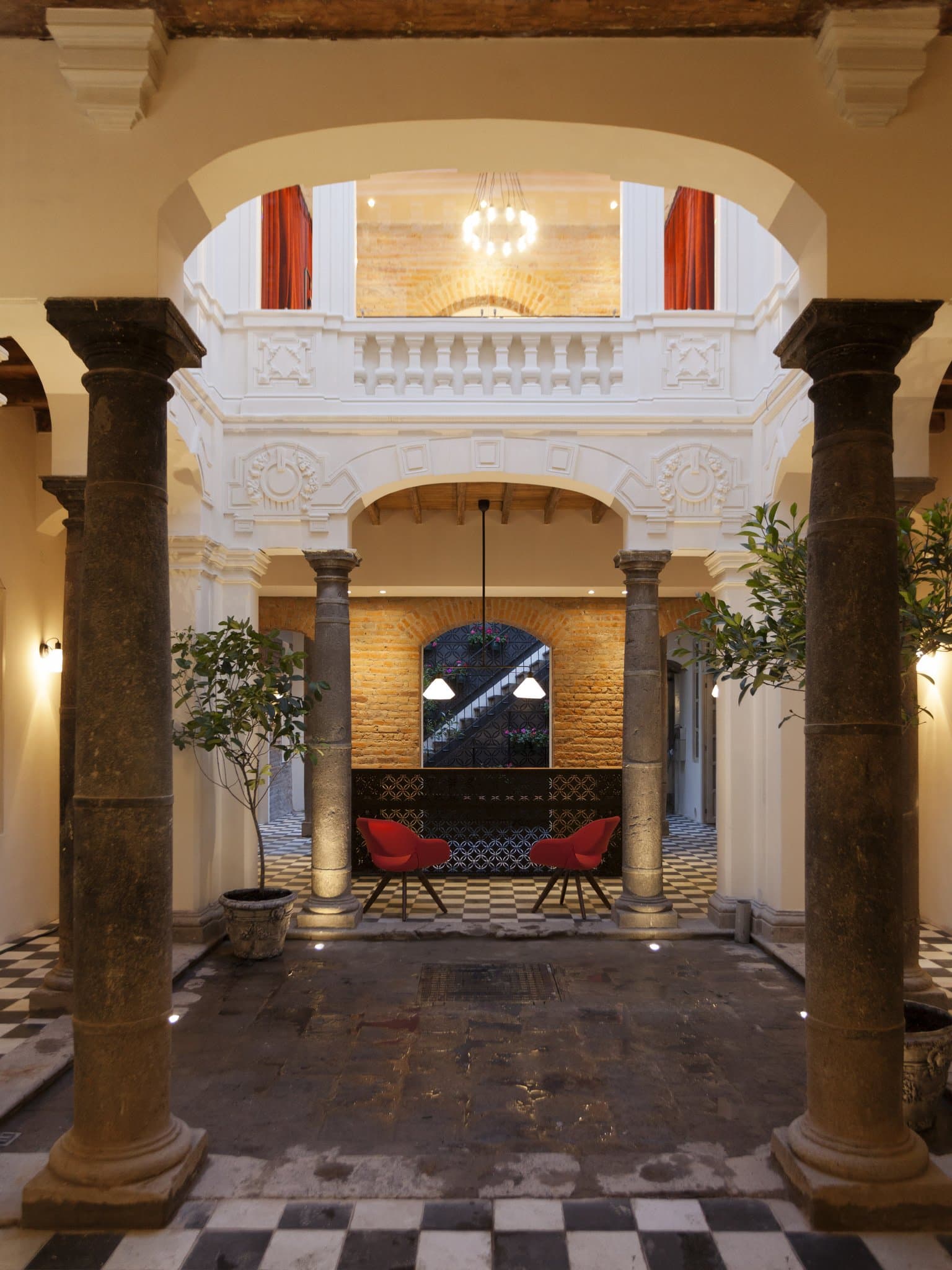 Central atrium of Carlota Hotel featuring industrial steel beams, a lush vertical garden, and a glass skylight illuminating the eco-chic interior.